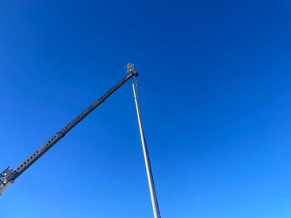 Grúa levantando un poste de iluminación de mástil alto en el estacionamiento de camiones ARDOT I-40