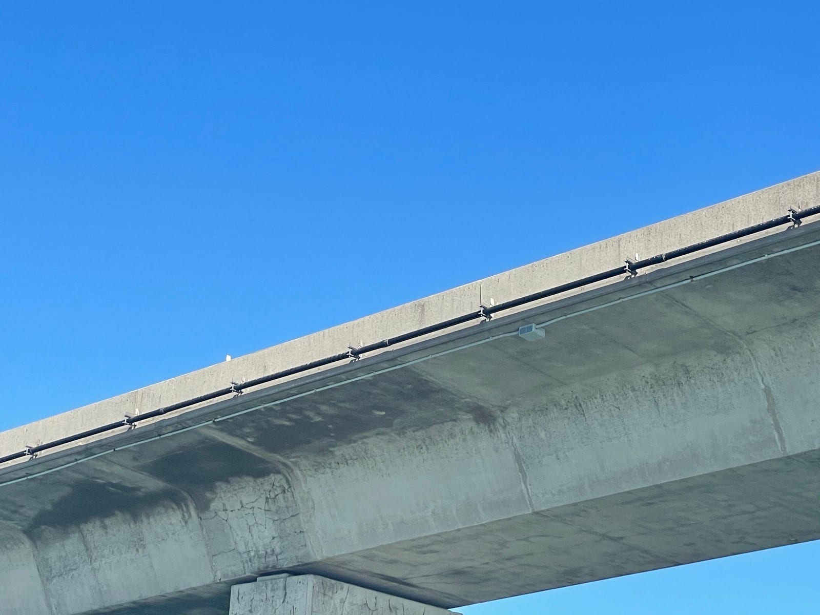 Network conduit installation beneath the bridge parapet