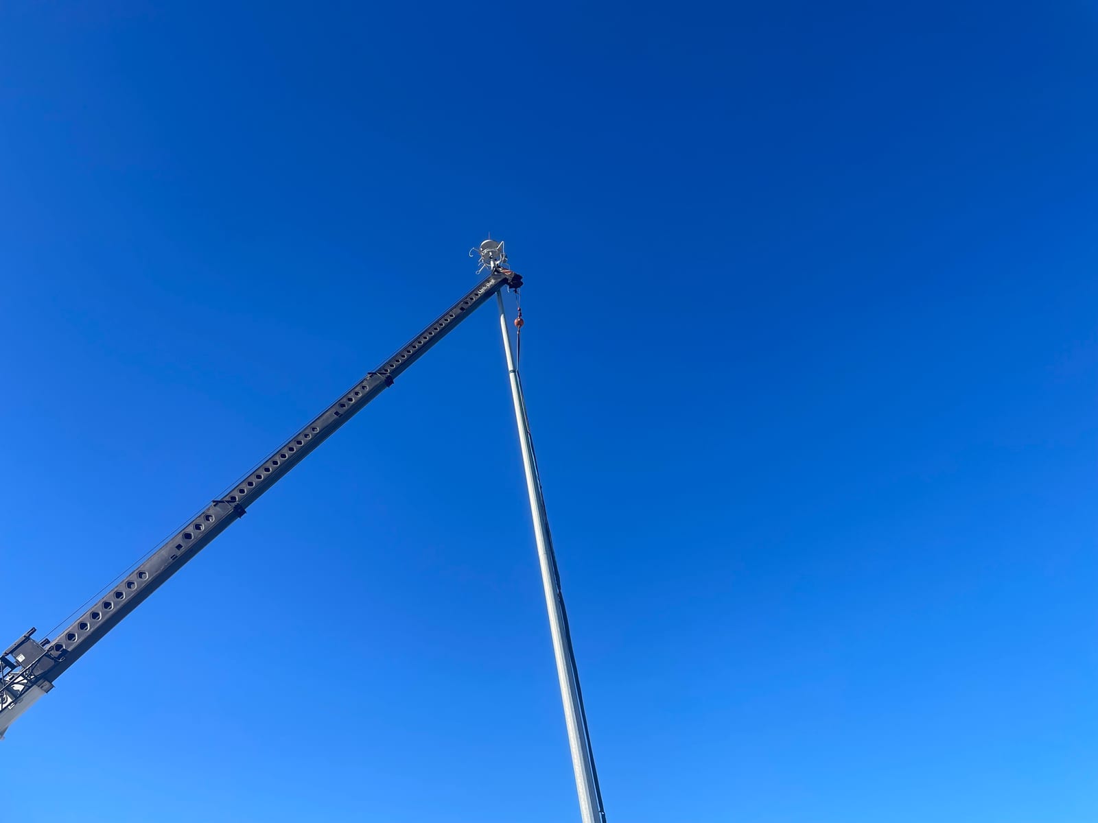 Crane lifting a high-mast lighting pole at the ARDOT I-40 truck parking facility