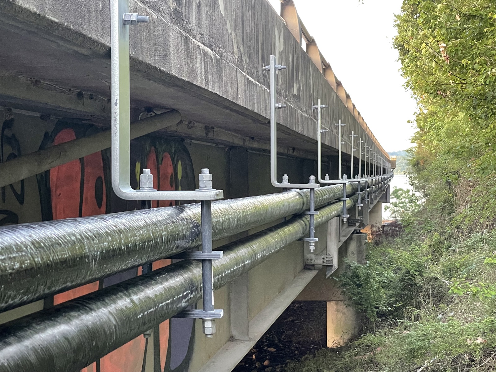Structure-mounted conduit and galvanized hanger system beneath the bridge